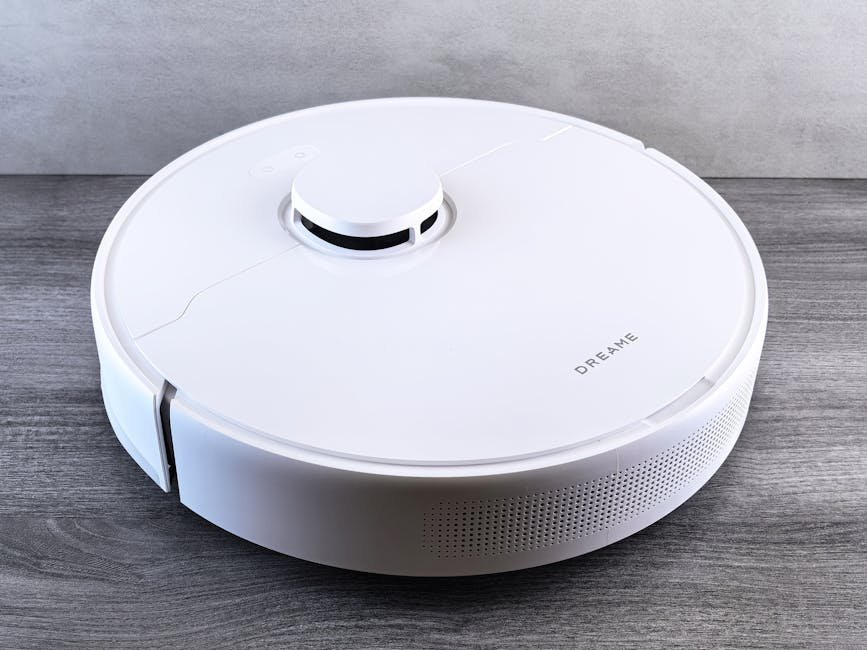 High-angle view of a sleek white robotic vacuum cleaner on a wooden floor, perfect for smart home setups.
