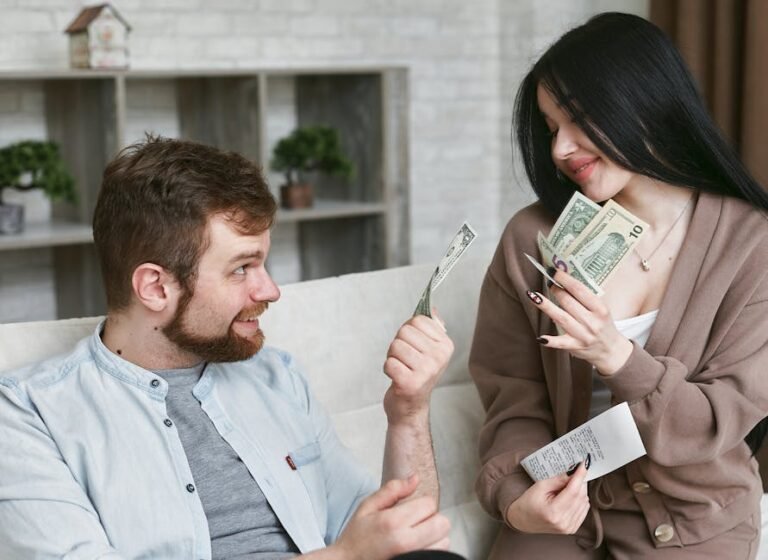 A cheerful couple managing their finances at home, holding cash and a receipt.