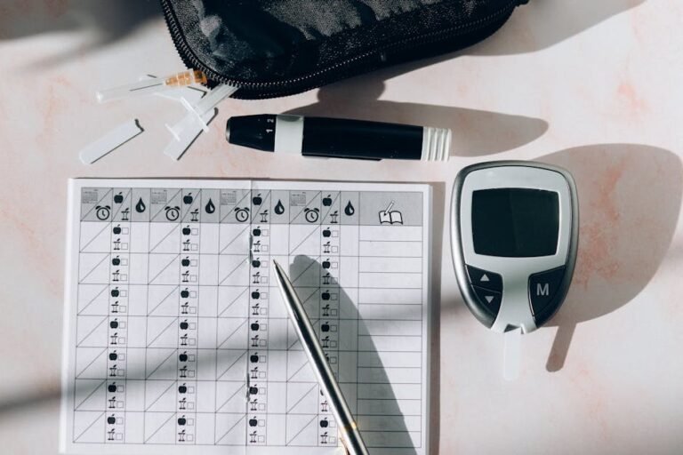 Close-up of a diabetes monitoring kit with glucometer, pen, and test strips on a table.