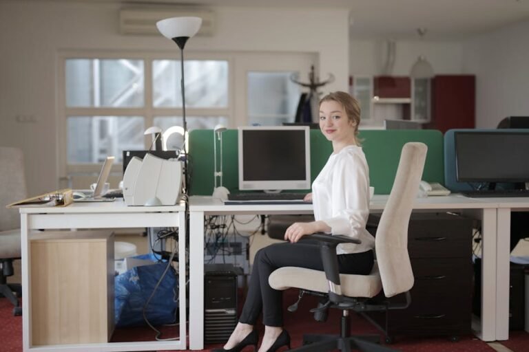 Confident businesswoman sitting at a desk in a modern office setting.