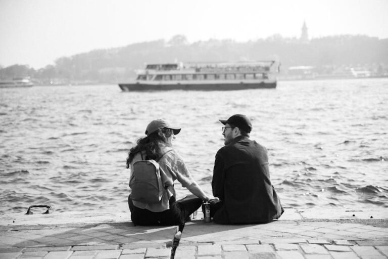 A couple sitting by the Bosphorus in Istanbul, enjoying the view with a ferry passing by. Perfect for travel and lifestyle themes.