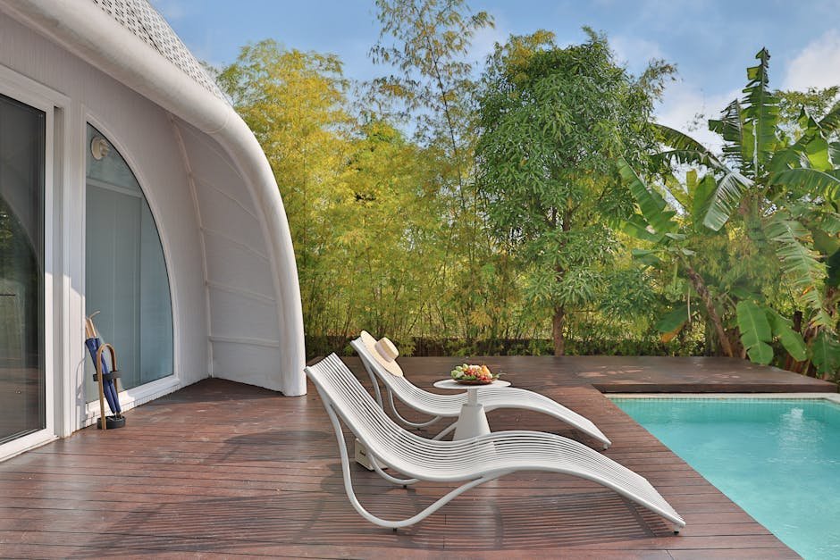 Serene outdoor poolside with modern lounge chairs and lush green surroundings.