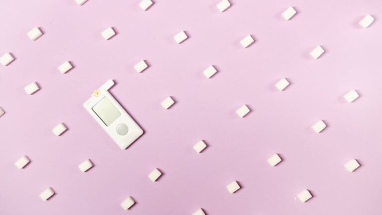 Flat lay of sugar cubes and glucometer on pink background symbolizing diabetes and health awareness.