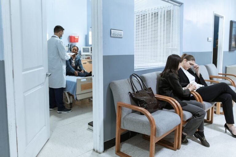 Doctor with patient in ICU, women in waiting area showing concern.