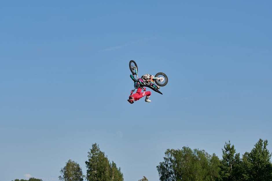 Daring motocross stunt against a clear blue sky, showcasing extreme sports excellence.