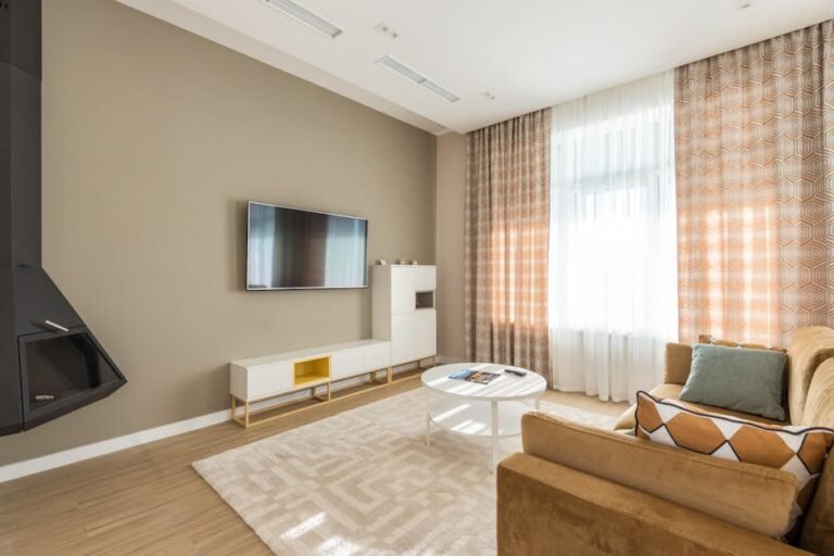 Bright modern living room with a sofa, coffee table, and large window curtains.