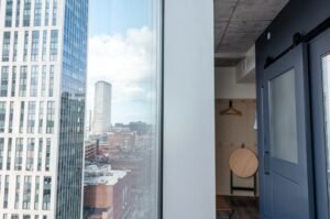 Contemporary Boston apartment interior with city skyline view through window, showcasing urban architecture.