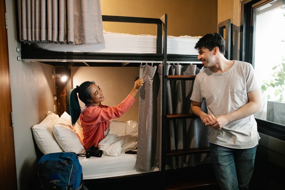 A cheerful moment shared between two friends in a cozy hostel room with bunk beds.