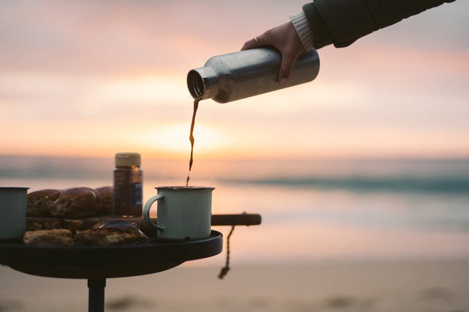 Enjoying a hot coffee in a rustic mug on the beach at sunrise, capturing a peaceful morning moment.