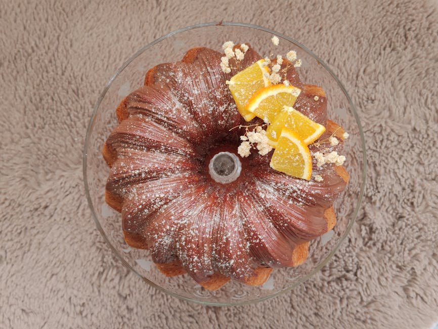 A delicious Bundt cake topped with orange slices and powdered sugar on a textured surface.