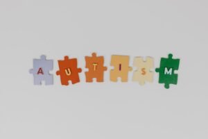 Colorful puzzle pieces spelling 'autism' on a white background, promoting awareness.