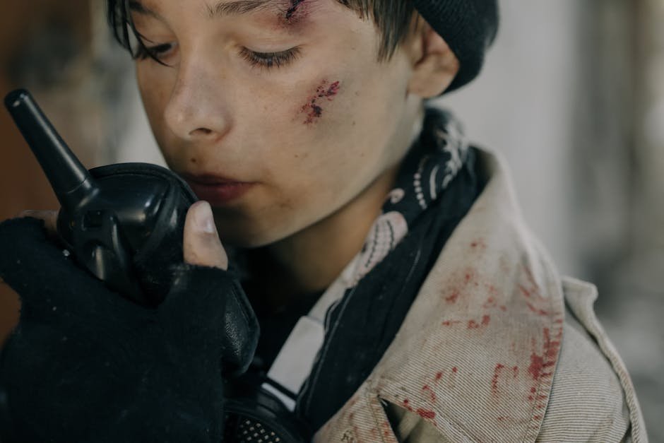 Close-up of a wounded teenager using a walkie talkie, conveying a post-apocalyptic sense of survival.